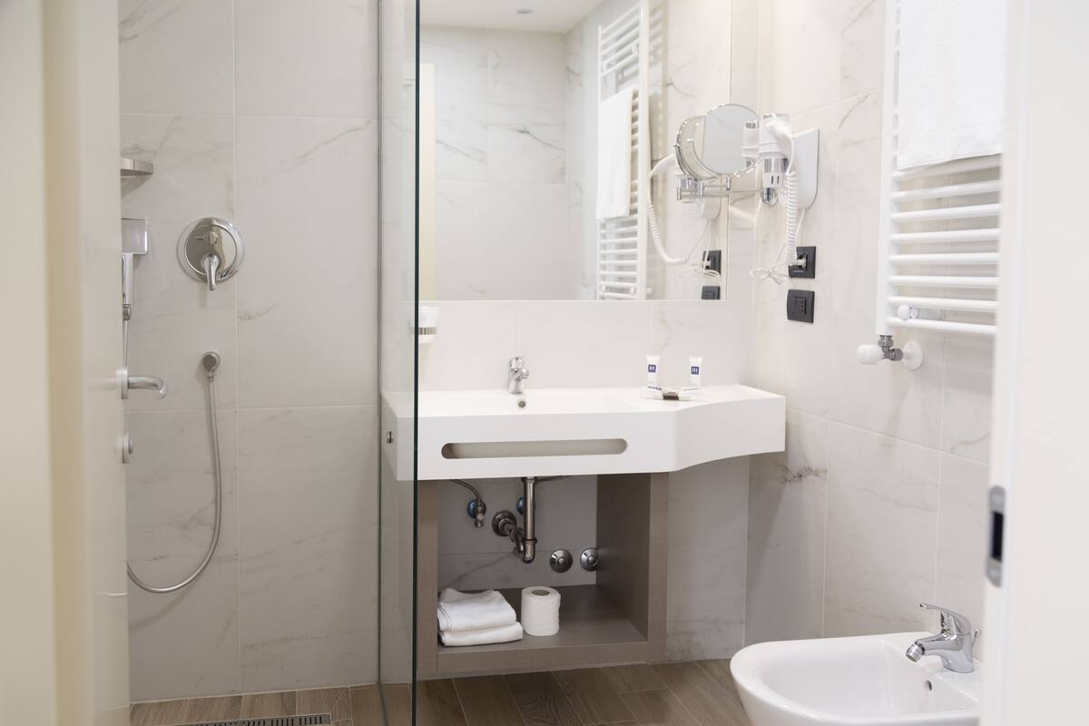 A modern bathroom with a shower, sink, and bidet.