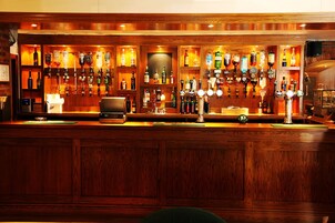 Una zona de bar con paneles de madera, varios dispensadores de licores y una caja registradora.