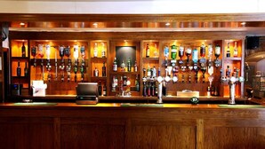 A bar with wooden paneling, multiple liquor bottles, and a variety of beer taps. - Beaufort Park Hotel (Mold)