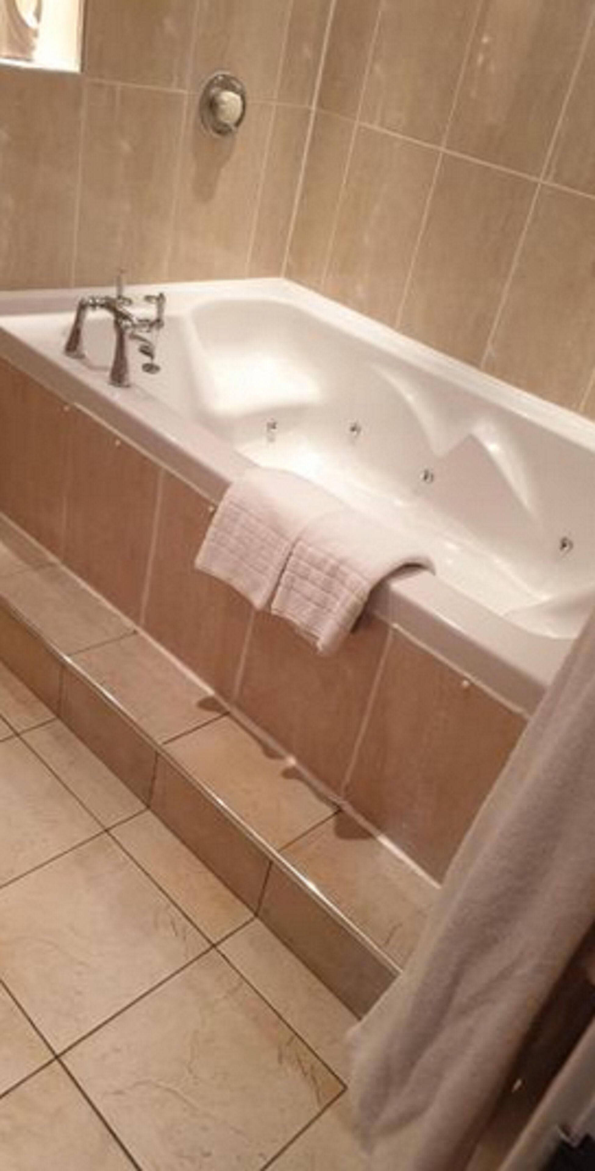 A bathroom with a large bathtub, a towel rack, and a toilet.