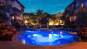 A swimming pool with a central water feature, surrounded by palm trees and a gazebo. - The Lakes Resort Cairns (Cairns North)