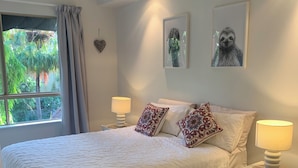 A bedroom with a large bed, two bedside lamps, a nightstand, a window with curtains, and a ceiling fan. - The Lakes Resort Cairns (Cairns North)