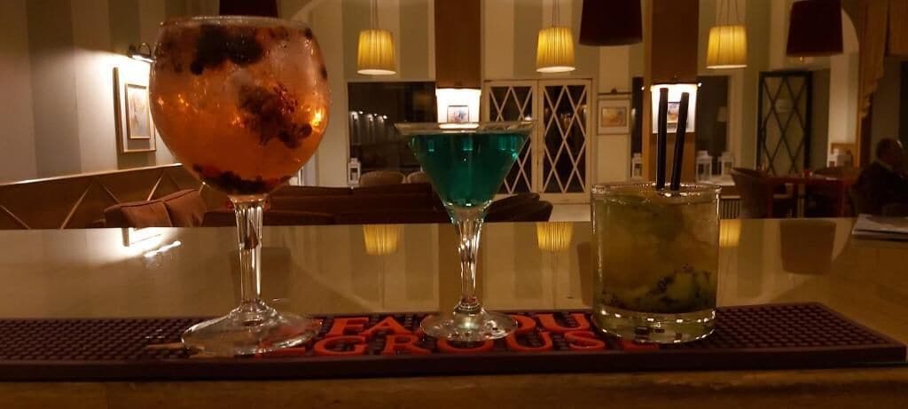 Drie cocktails op een barkruk met een rode mat waarop 'HEADQUARTERS' staat.