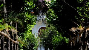 A pathway leading to a fountain surrounded by lush greenery and a building with a yellow facade. - Hotel das Termas Curia (Anadia)