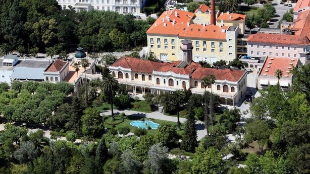 An aerial view of a historic building complex with a central courtyard, a swimming pool, and surrounding greenery. - Hotel das Termas Curia (Anadia)