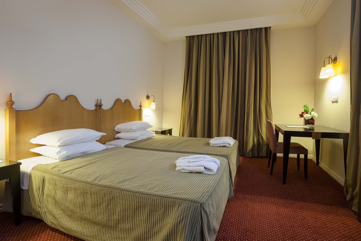 A hotel room with a large bed, two bedside tables, a desk, and a chair.