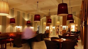 A restaurant with high ceilings, red pendant lighting, and a mix of seating arrangements including tables and booths. - Hotel das Termas Curia (Anadia)