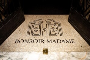 A tiled floor with the words "BONSOIR MADAME" and a decorative emblem. - Hôtel Bonsoir Madame (Paris)