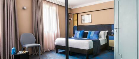 Una habitación de hotel con una cama, una silla, un escritorio y una puerta.