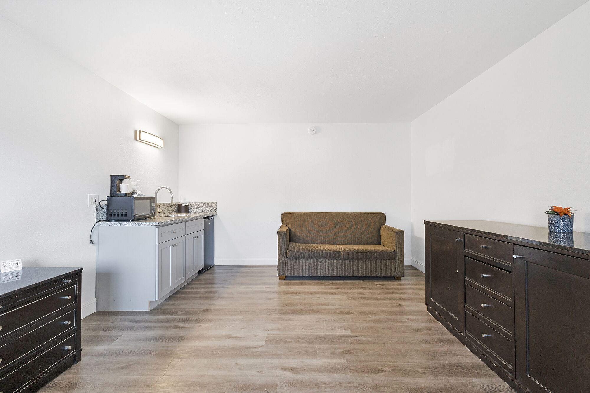 A compact living space with a kitchenette, a sofa, and a cabinet.