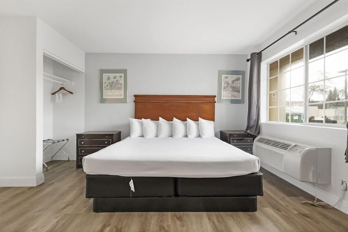 Quarto com uma cama grande, mesas de cabeceira, radiador e janela com vista.