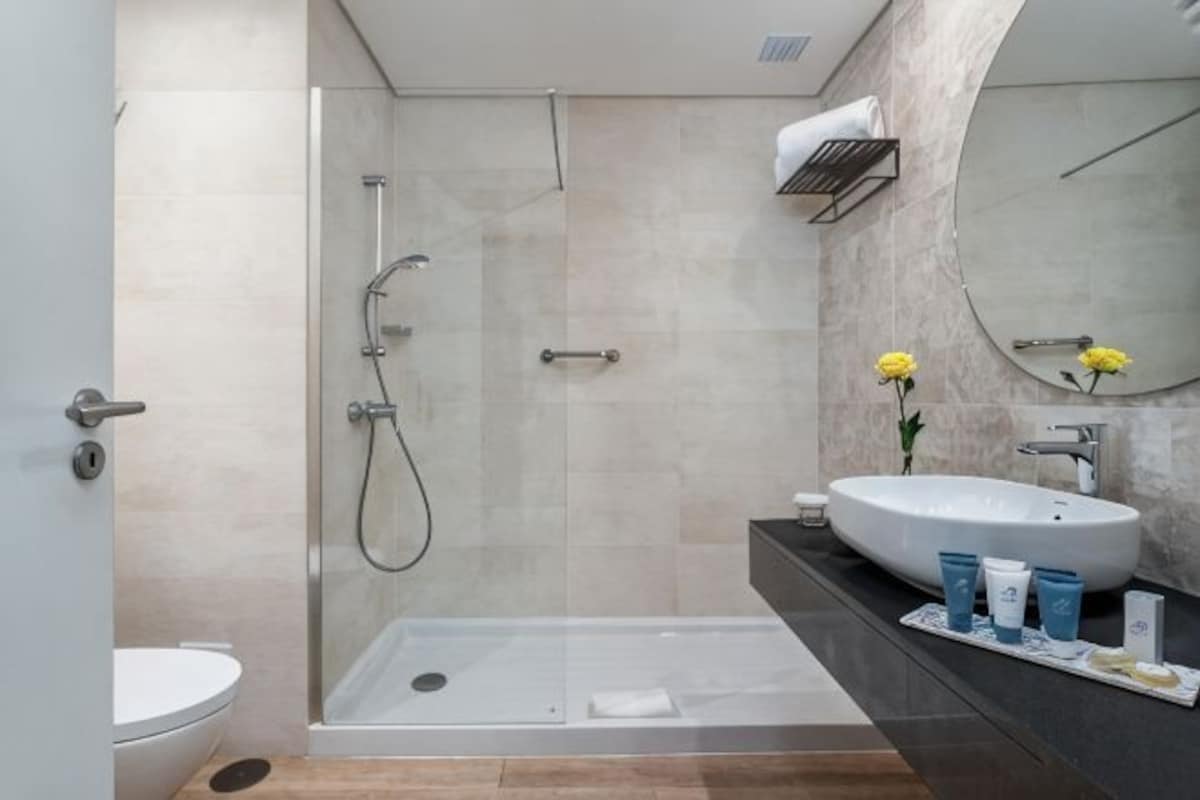 A modern bathroom with a glass shower enclosure, a white sink, and a large mirror.