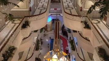 Un atrio de varios niveles con una escalera central, iluminación decorativa y una fuente de agua.