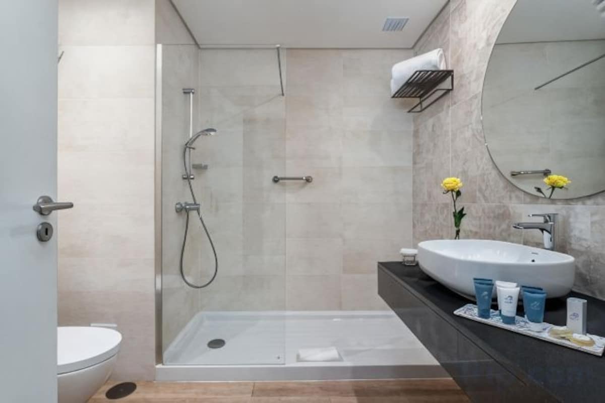 A modern bathroom with a glass-enclosed shower, a white sink, and a large mirror.