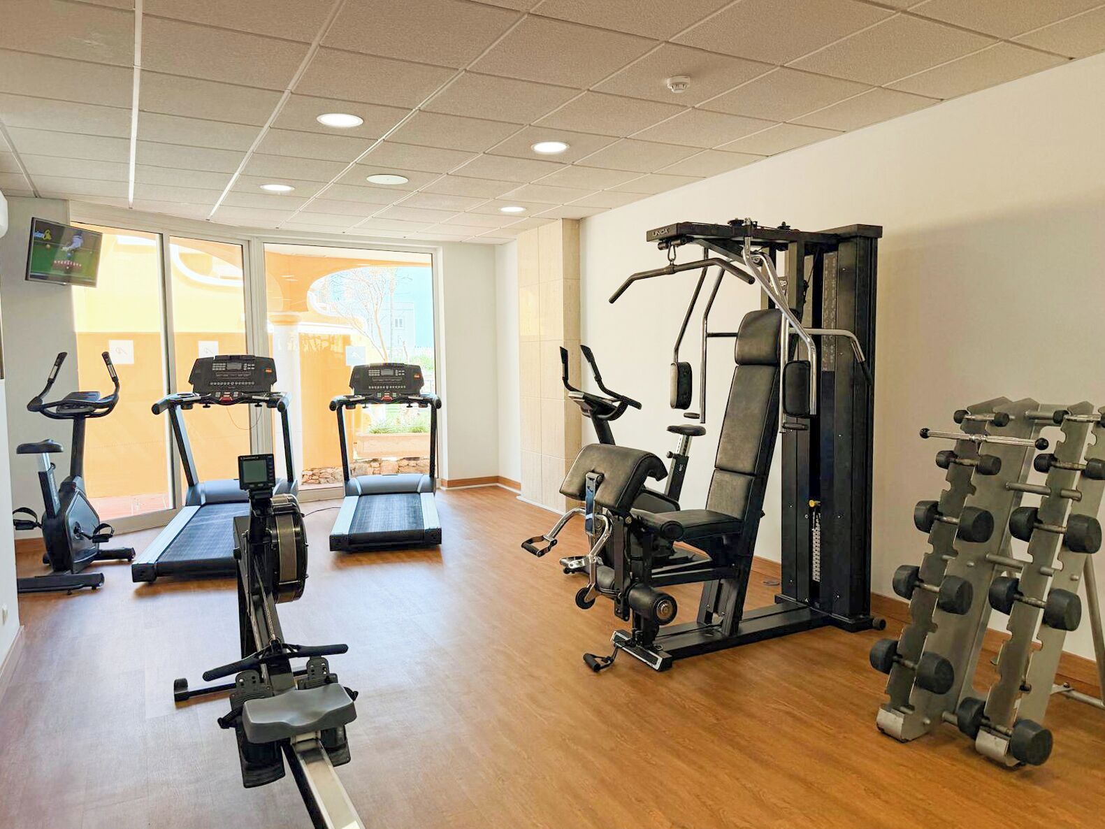 Une salle de sport équipée de tapis de course, d’une machine de musculation et d’un porte-haltères.