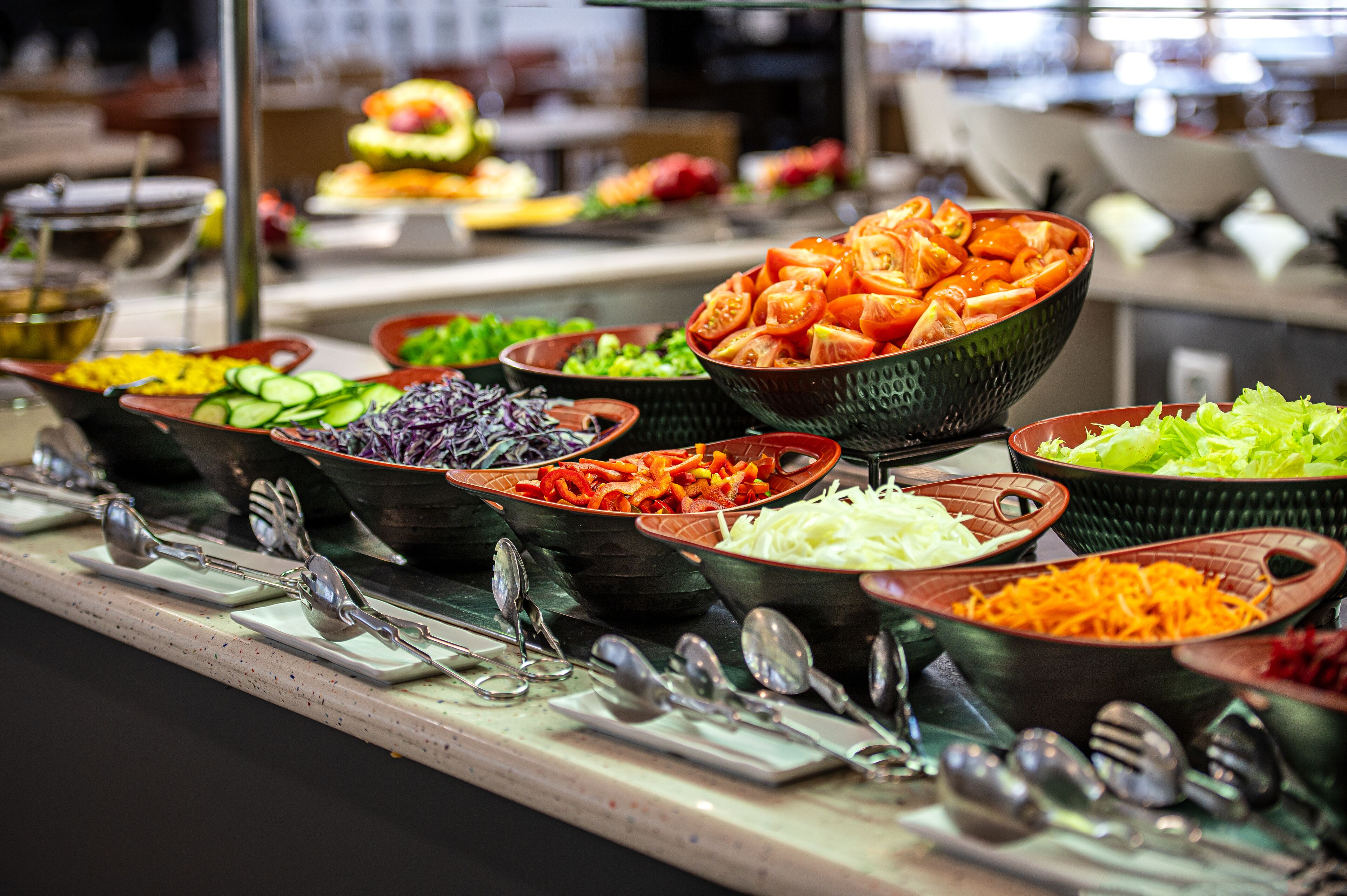 Buffet amb diversos plats, incloent verdures, carns i amanides.