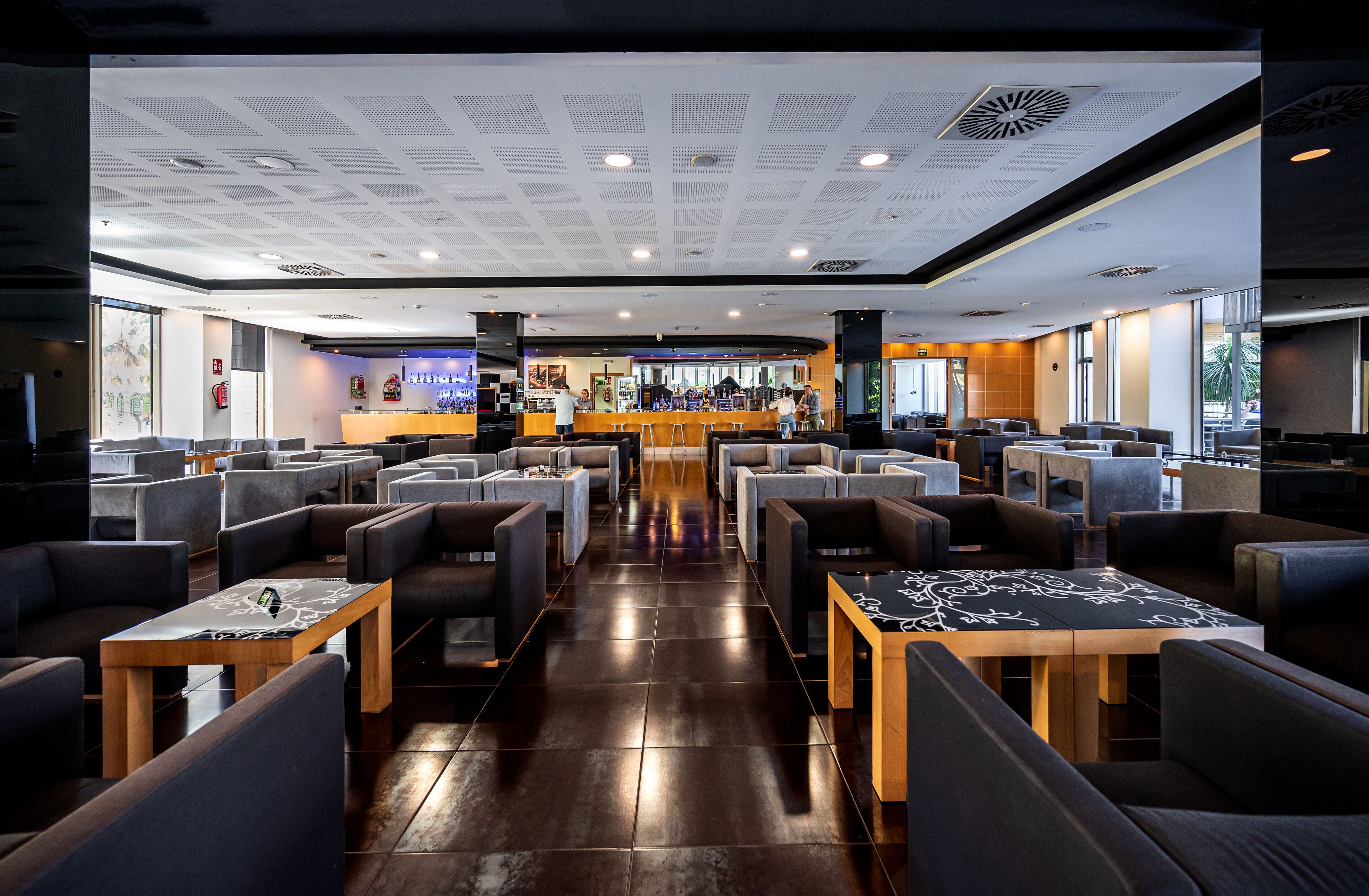 Un restaurante moderno con zona de bar, diversas opciones de asientos y un diseño limpio y contemporáneo.