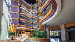 A multi-level atrium with a modern design, featuring curved balconies and a central atrium with a reception desk and seating area. - Albir Playa Hotel & Spa (L'Alfas del Pi)