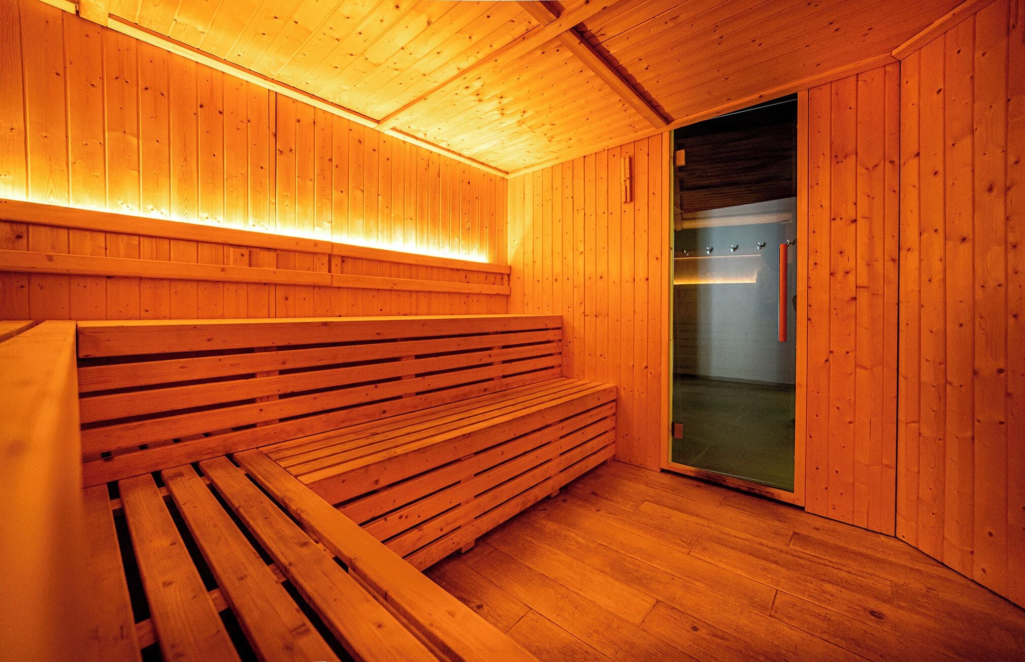 Uma sauna com bancos de madeira e porta de vidro.