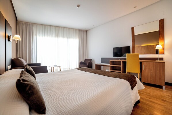 A hotel room with a large bed, a desk with a computer, a TV, and a seating area with chairs. - Albir Playa Hotel & Spa (L'Alfas del Pi)