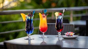 Three colorful cocktails on a table with a blurred green background.