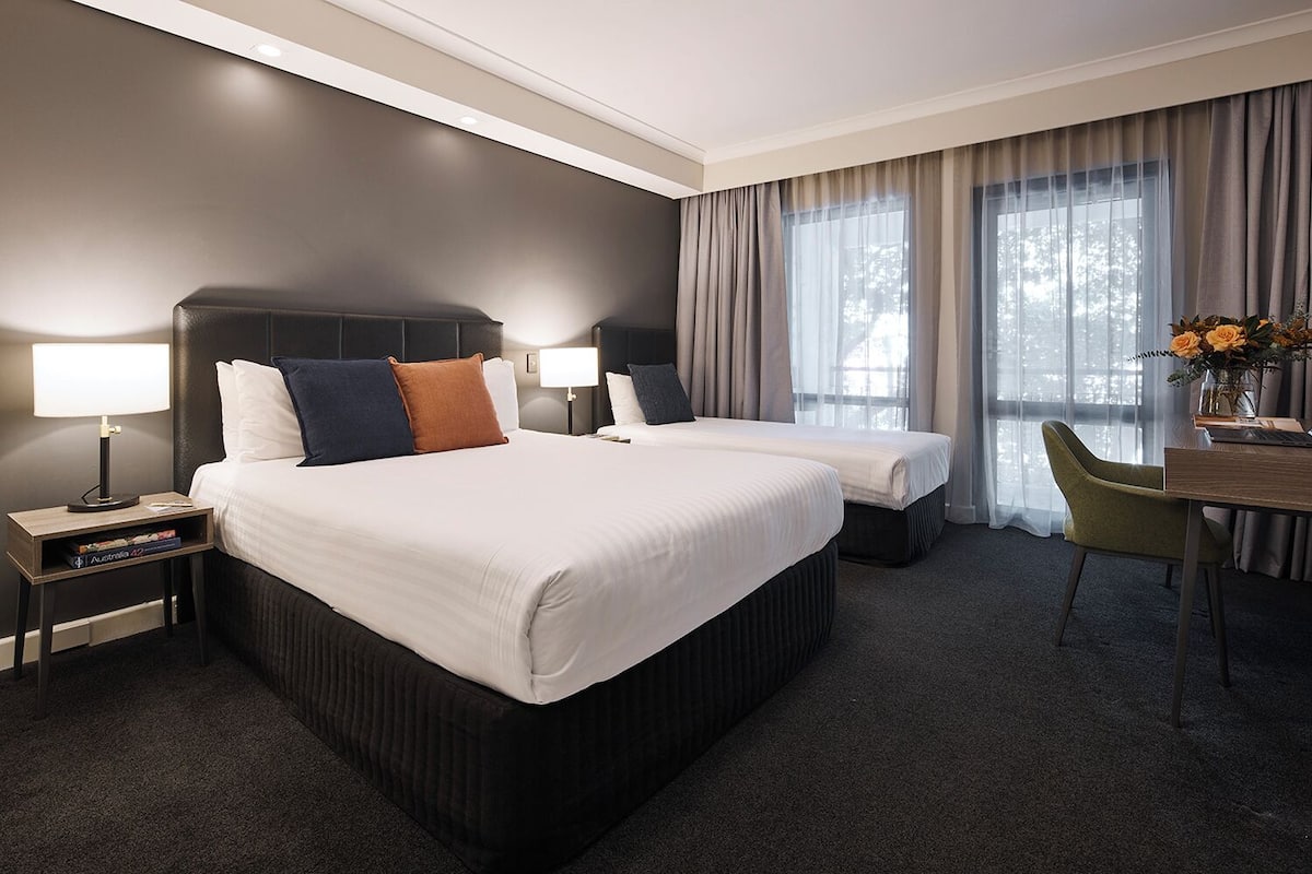 A hotel room with a large bed, two bedside tables, a desk, and a chair.