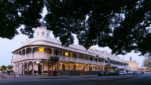 Un hotel histórico con una torre destacada, varios balcones y zonas de estar al aire libre.