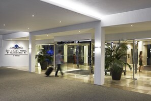 The entrance of the Eplanade Hotel with a glass door, a potted plant, and a sign indicating the hotel's name.