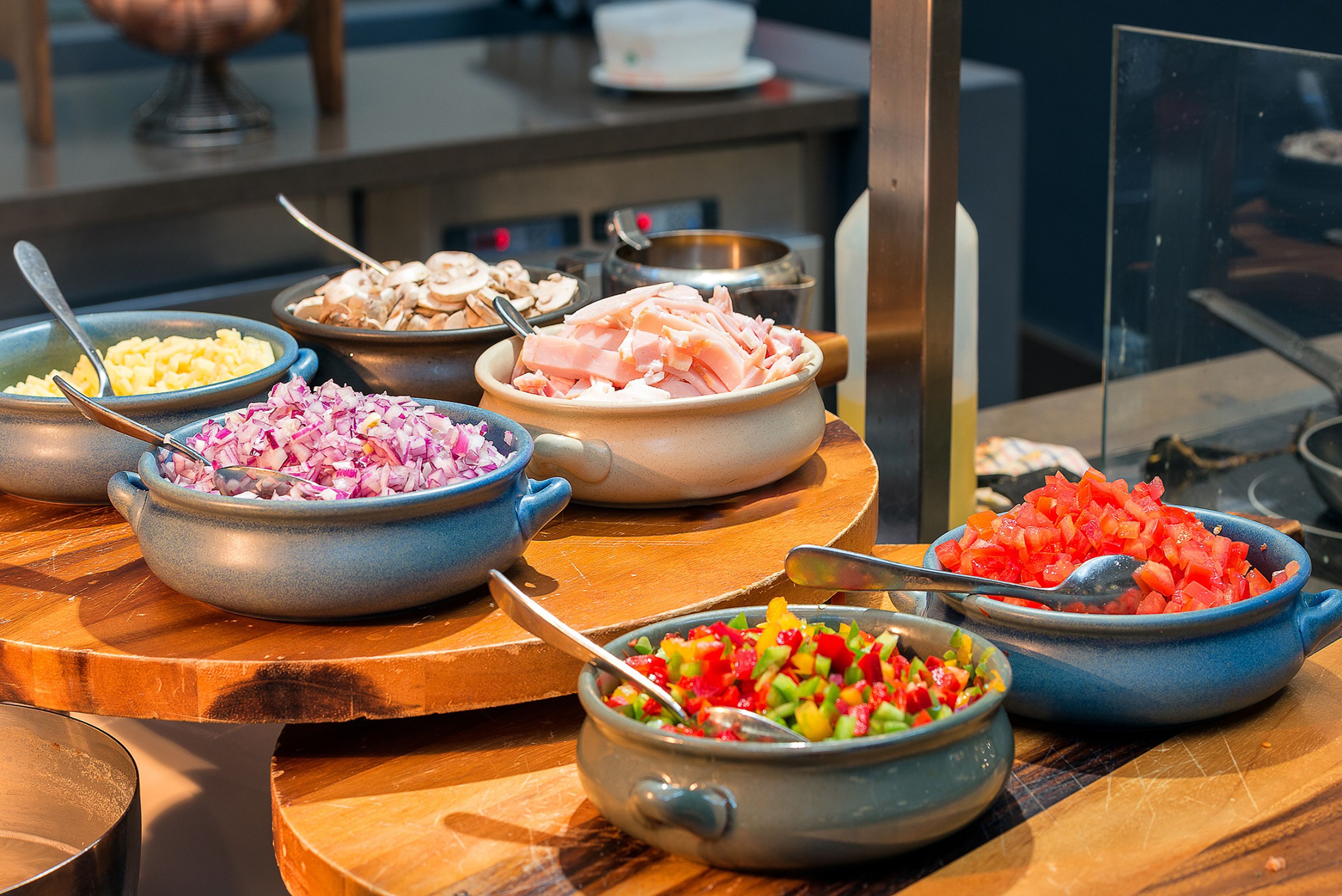 A buffet with various dishes including chopped vegetables, sliced meats, and other prepared foods.