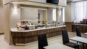 A hotel breakfast area with a buffet counter, seating, and a television above. - Residence Inn by Marriott Houston Downtown/Convention Center (Houston)