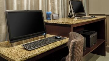 A workspace with two desktop computers, a keyboard, a mouse, and a printer on a granite countertop.