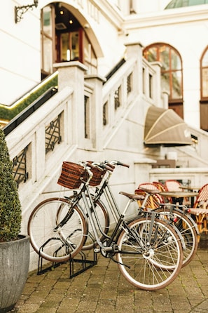 A bicycle parked next to a building with a staircase, outdoor seating, and a potted plant. - Killarney Plaza Hotel and Spa (Killarney)