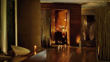 Un interior de madera con una mesa de recepción, una pequeña mesa con una vela y una planta en maceta.