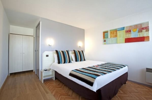 A bedroom with a bed, bedside tables, a wardrobe, and a wall-mounted artwork. - Sure Hotel by Best Western Biarritz Aeroport (Biarritz)