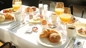 A breakfast table with croissants, orange juice, and coffee. - Hotel Chariot (Aalsmeer)