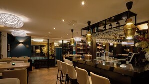 A bar area with a long counter, multiple bar stools, and a variety of bottles and glasses on shelves. - Hotel Chariot (Aalsmeer)
