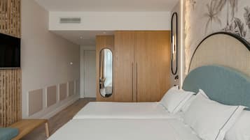 Una habitación de hotel moderna con una cama grande, un televisor montado en la pared y un armario de madera.