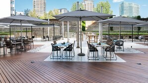An outdoor patio with wooden flooring, tables, chairs, and umbrellas. - Hotel Vincci Maritimo (Barcelona)