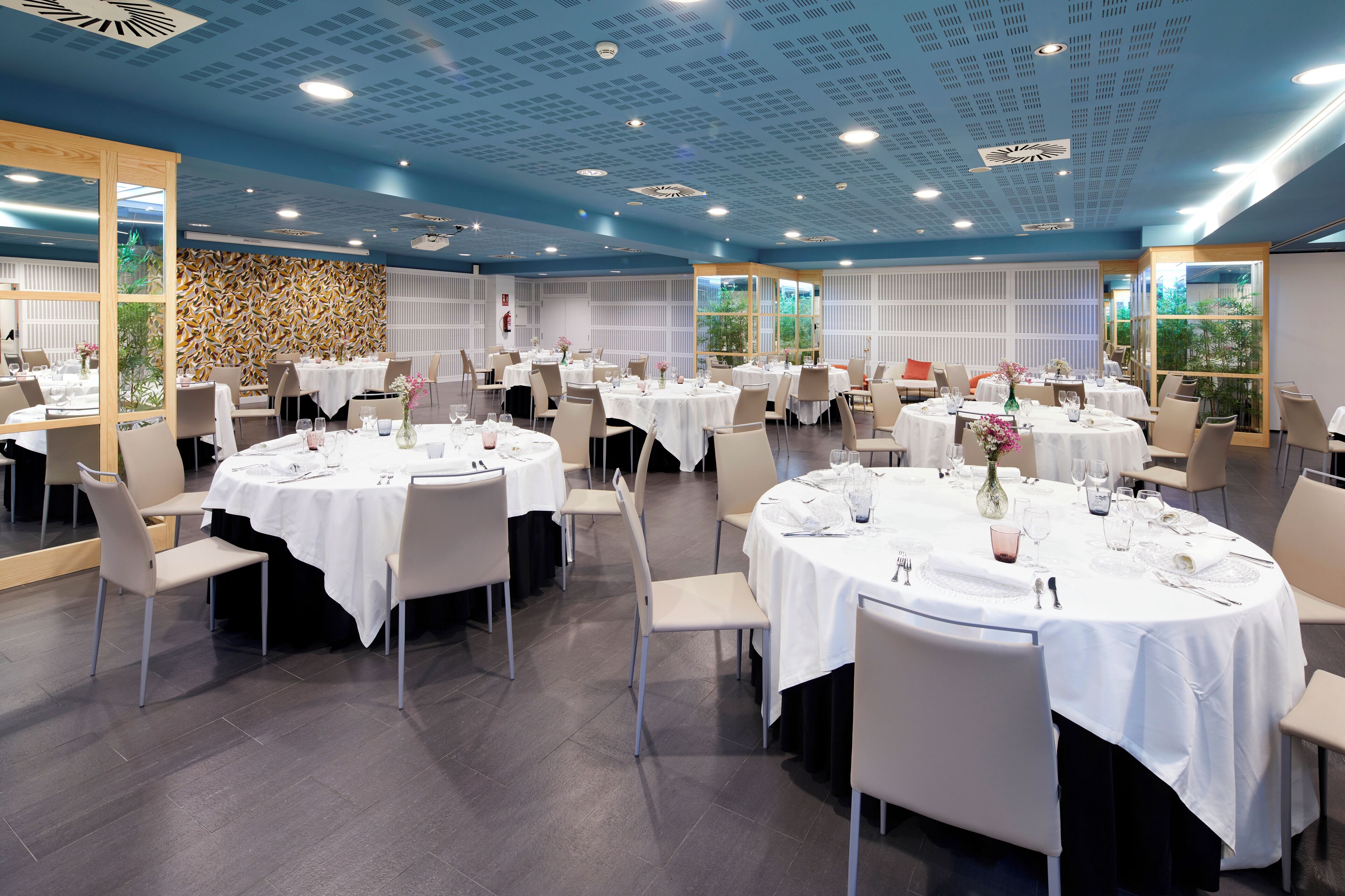 Un comedor amplio con mesas redondas, manteles blancos y sillas modernas.