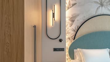 Une chambre moderne avec une armoire en bois, une table de chevet, un lit doté d’une tête de lit turquoise et un luminaire fixé au mur.