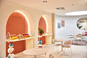A modern interior with round tables and chairs, a bar area with drinks, and a sign for 'SALA CONDOR'.