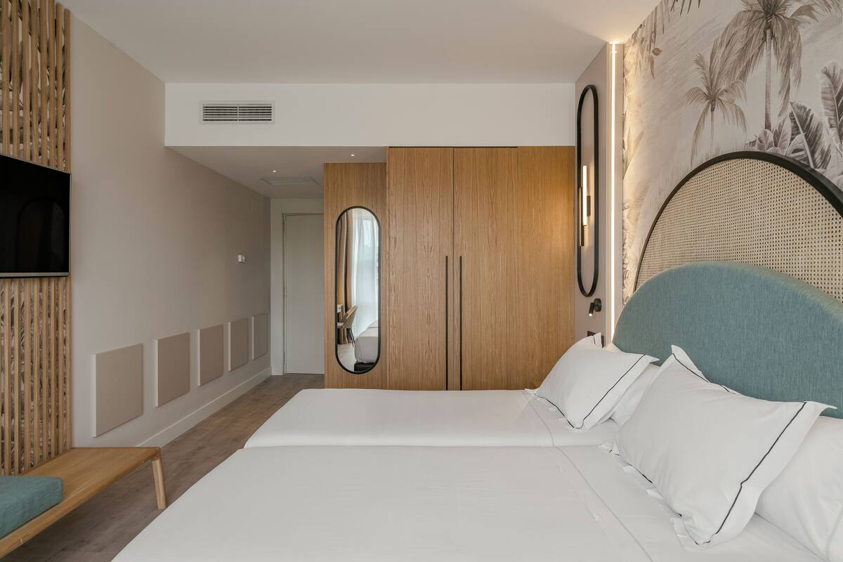 Moderni hotellihuone, jossa on suuri sänky, puinen vaatekaappi, peili ja televisio.