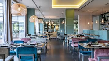 Un restaurante moderno con una barra central, diversas opciones de asientos y una variedad de lámparas colgantes.