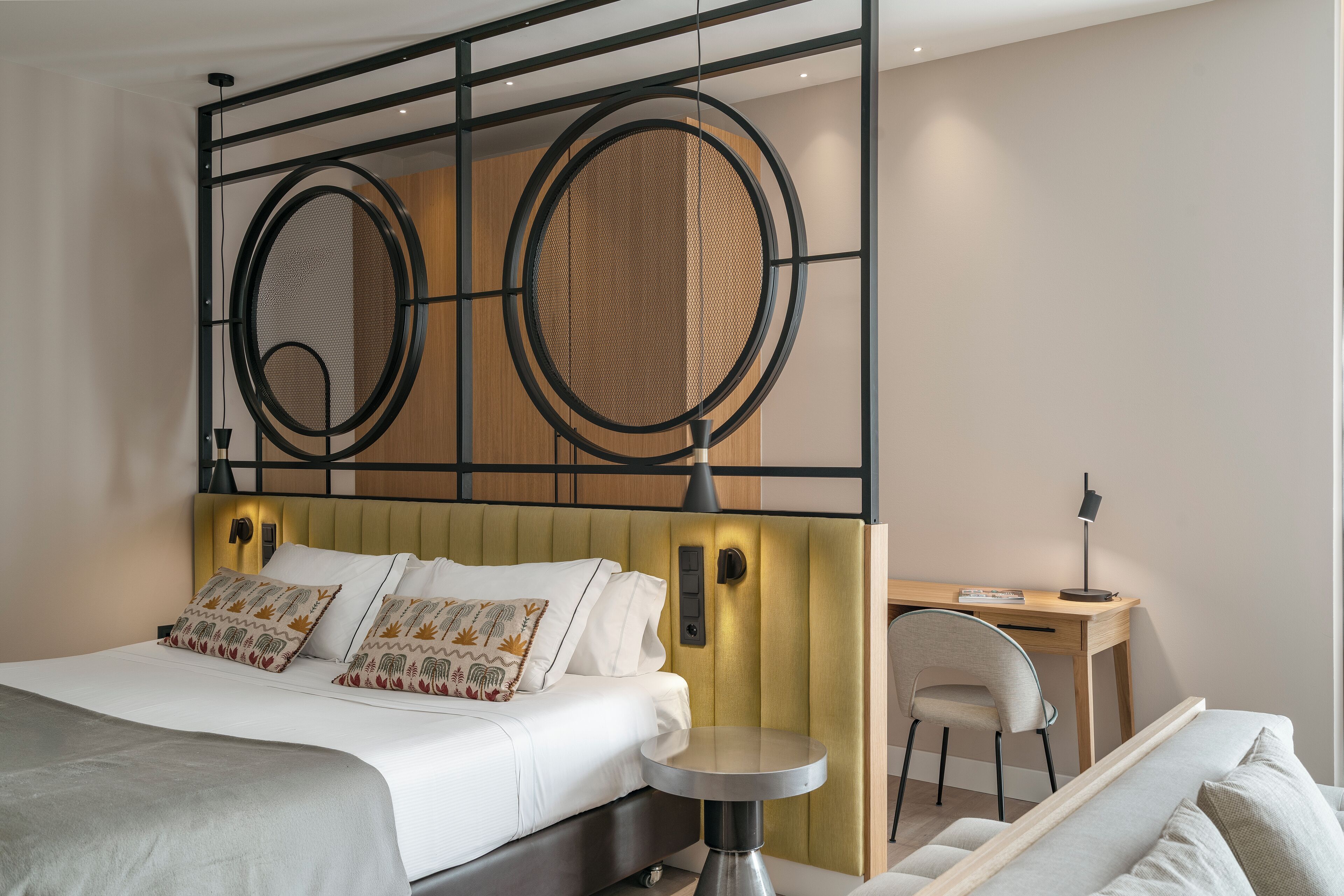 A modern hotel room with a bed, a desk, and a chair.