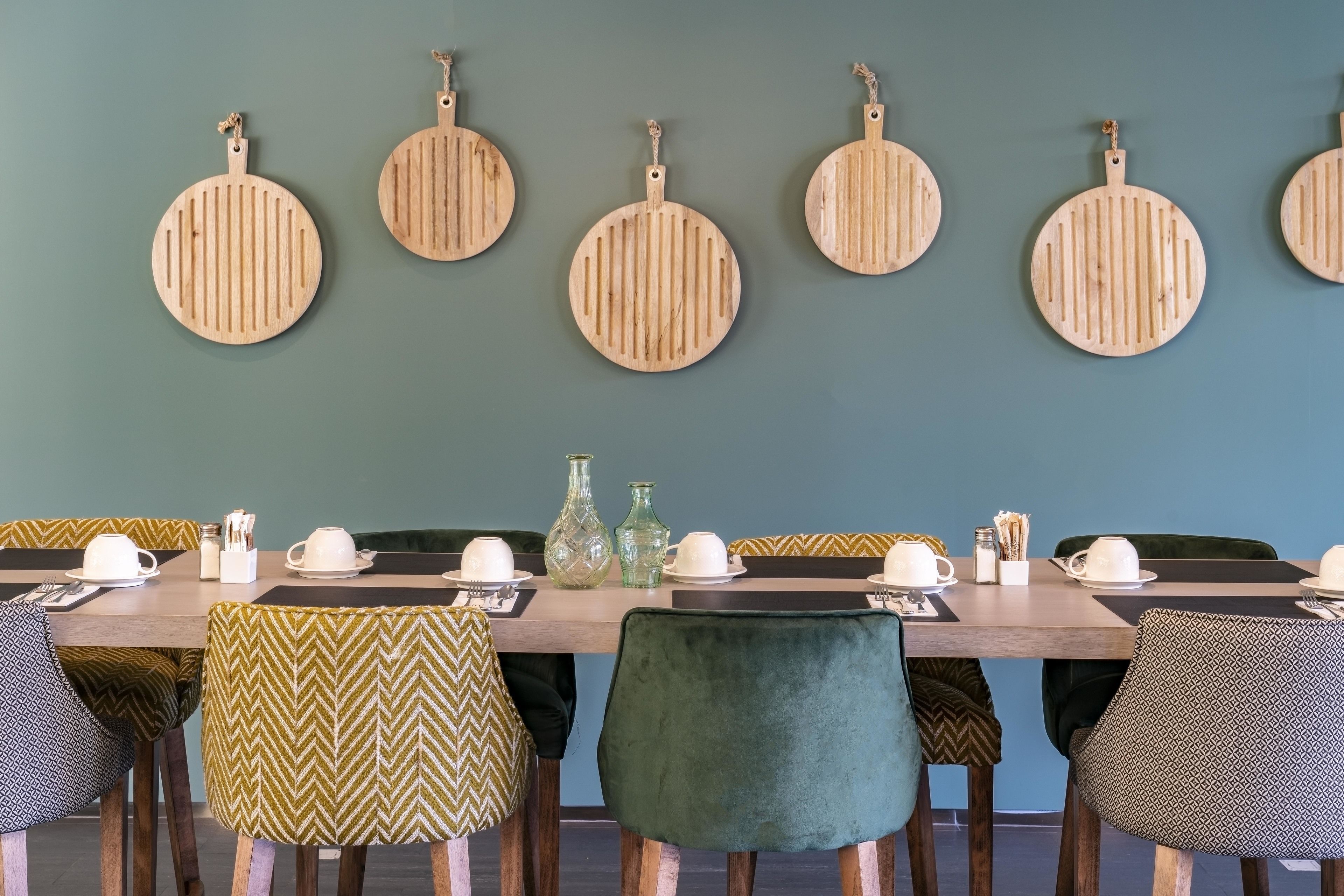Un comedor con una mesa larga, varias sillas y una pared decorada con adornos de madera circulares.
