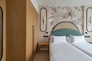 A bedroom with a bed, wooden wardrobe, and a small bedside table.