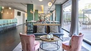A modern interior with a bar area, seating, and large windows. - Hotel Vincci Maritimo (Barcelona)
