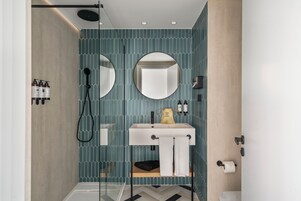 Un bagno moderno con doccia, lavandino e due specchi.