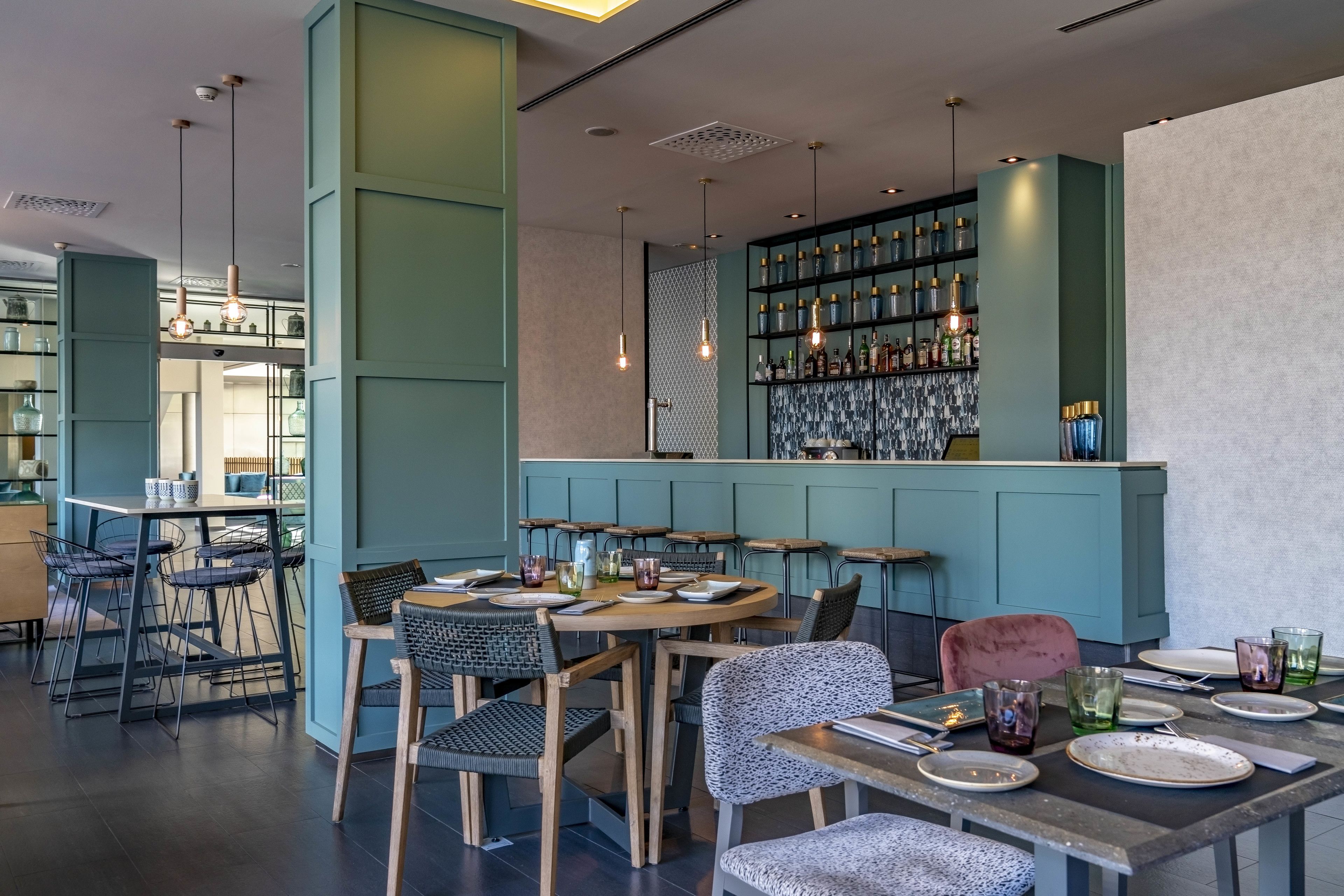 A modern restaurant with a bar area, wooden tables, and chairs.