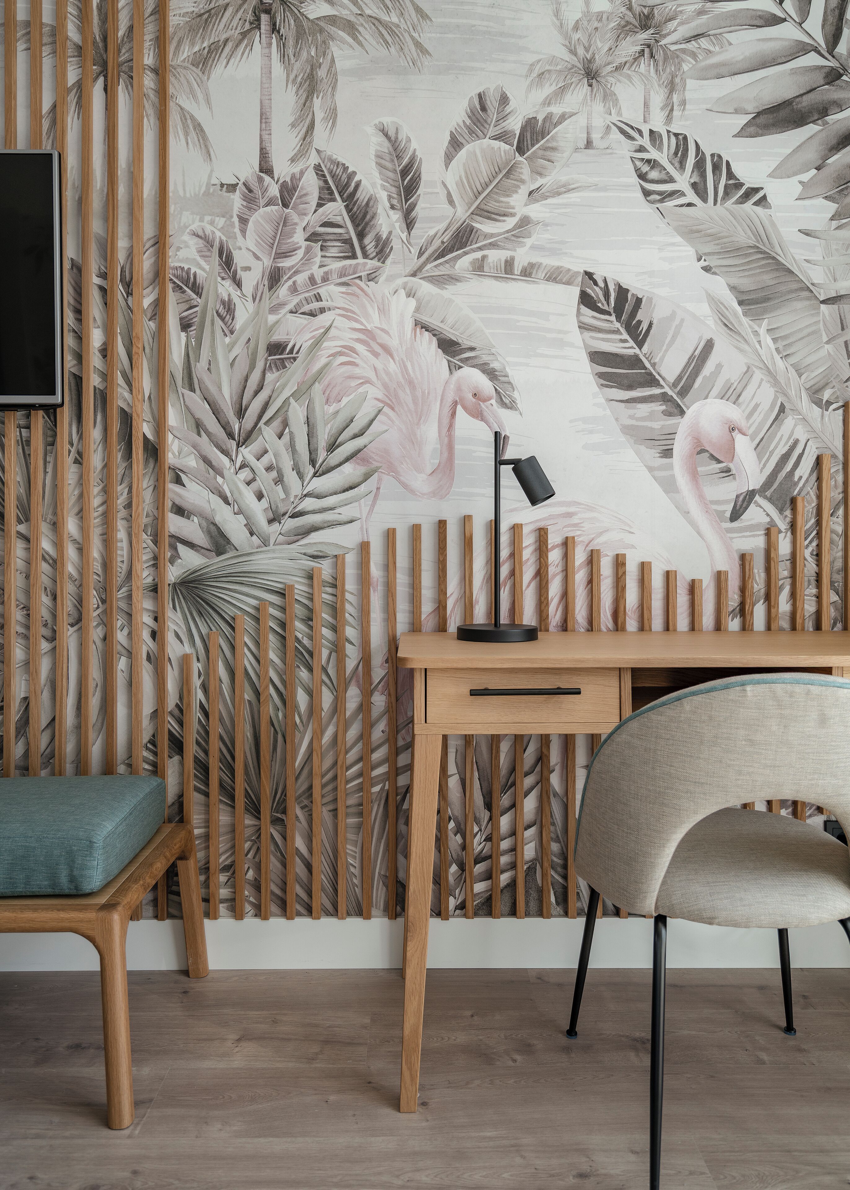 Une pièce avec un bureau en bois, une chaise et un mur orné d’une fresque aux motifs tropicaux.